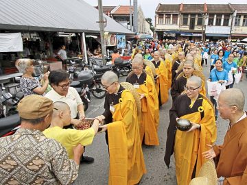 Devotees offering food alms and money to the novice monks and nuns during a procession from Penang Buddhist Association in Anson Road to Kek Lok Si Temple in Air Itam, Penang./Picby:CHAN BOON KAI/1 December 2019.