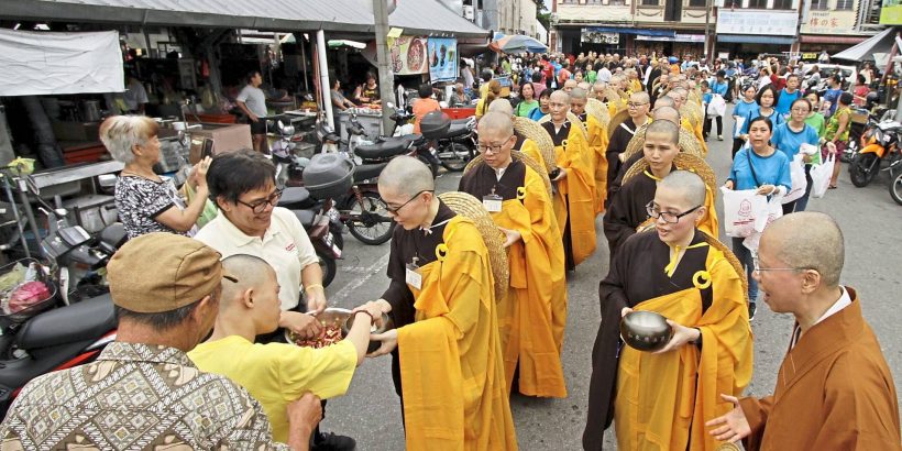 Devotees offering food alms and money to the novice monks and nuns during a procession from Penang Buddhist Association in Anson Road to Kek Lok Si Temple in Air Itam, Penang./Picby:CHAN BOON KAI/1 December 2019.